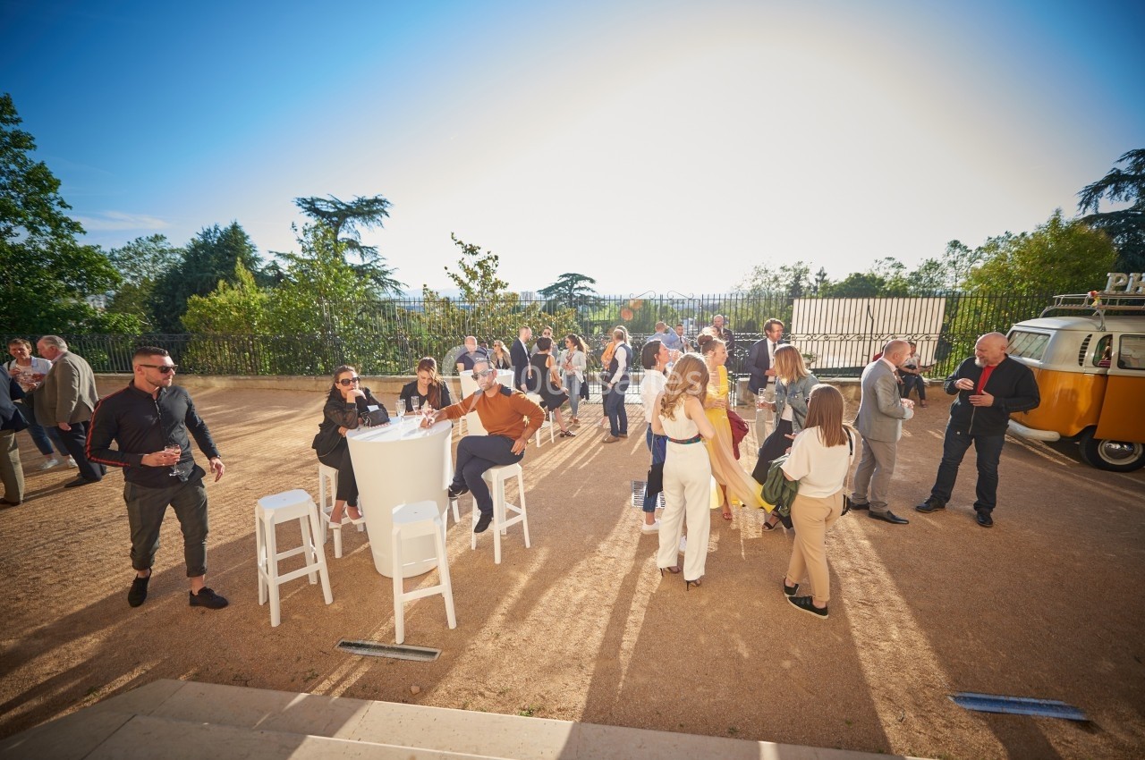Groupe de personnes discutant et partageant un moment convivial en extérieur, sous un ciel ensoleillé.