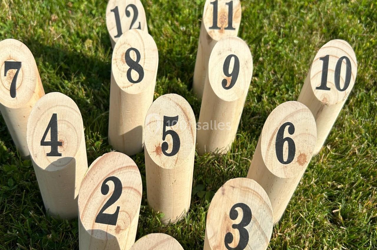 Quilles numérotées en bois disposées en cercle sur une pelouse verte.