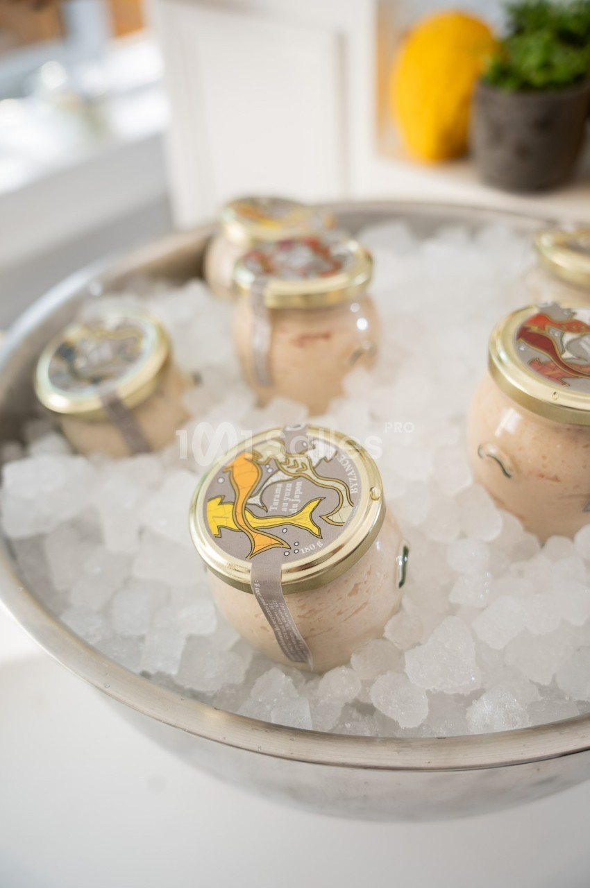 Des pots en verre scellés contenant des produits alimentaires, placés sur de la glace dans un bol en métal.