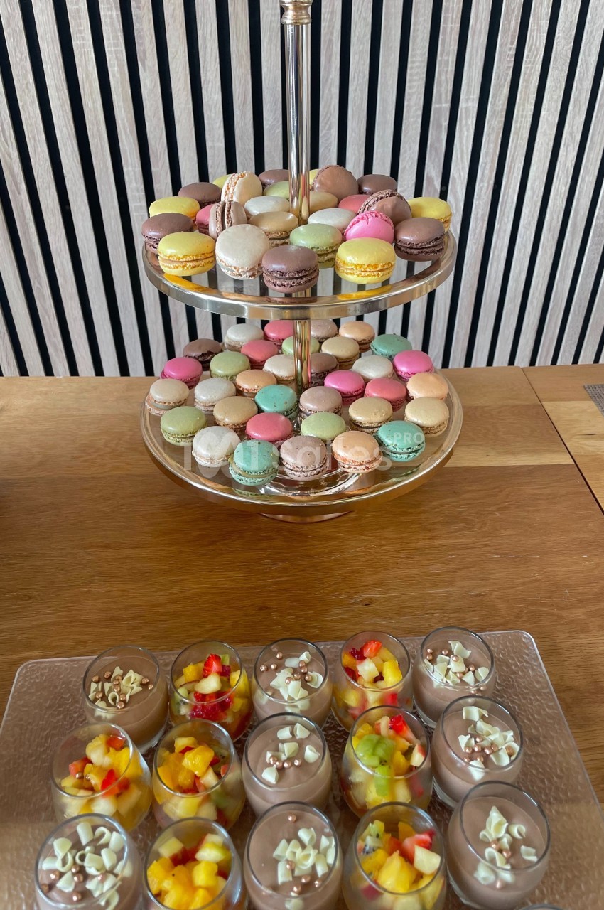 Plateau à deux étages de macarons colorés et verrines de mousse au chocolat garnies de fruits et éclats de chocolat.
