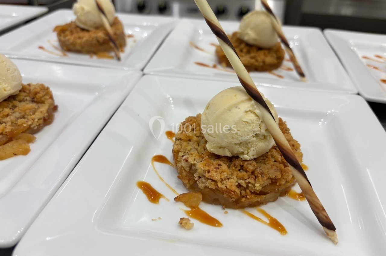 Desserts individuels composés de crumble aux pommes, boule de glace vanille et décoration en chocolat, servis sur assiettes…
