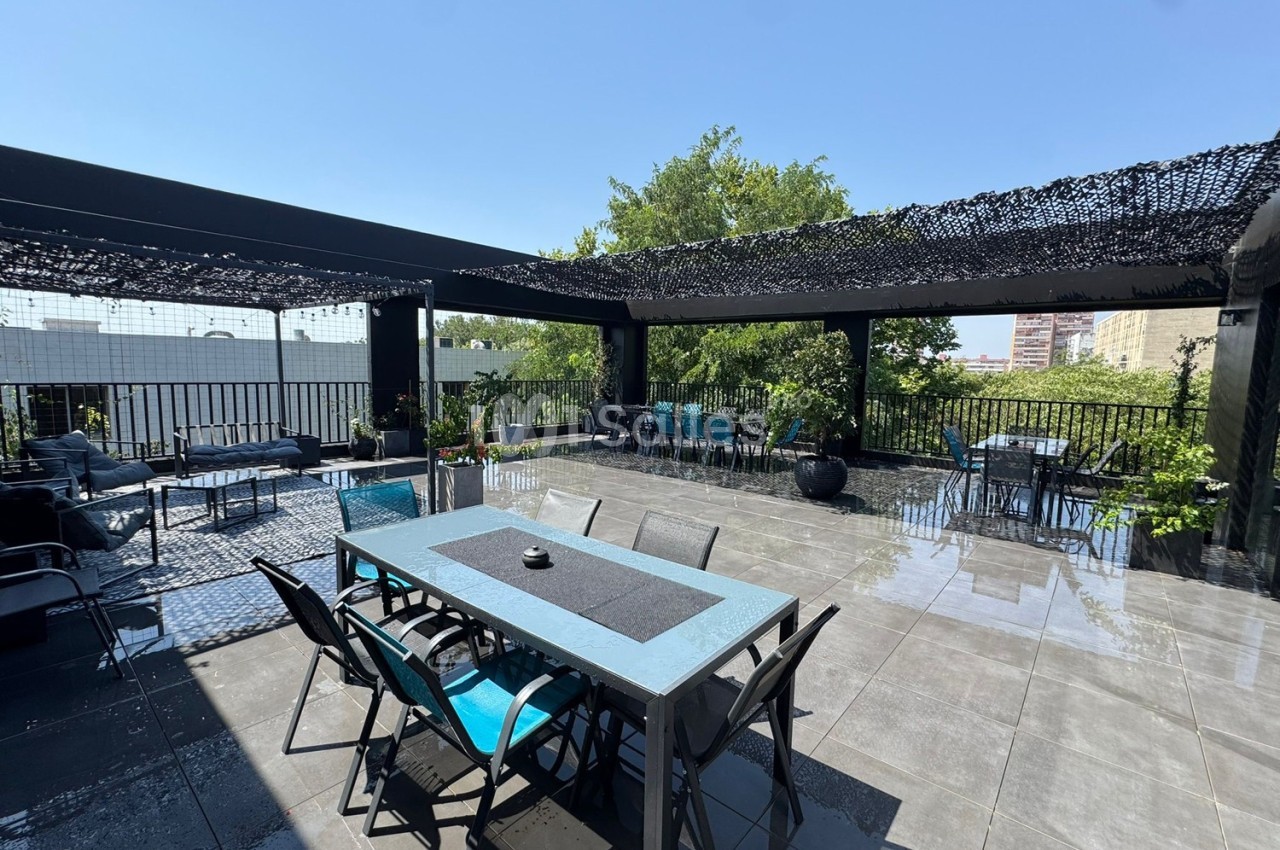 Terrasse spacieuse avec tables, chaises et pergola, entourée de verdure et baignée de lumière naturelle.