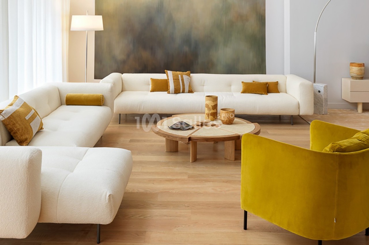 Salon moderne avec canapé blanc en L, fauteuil jaune, table basse en bois et décoration aux tons naturels.