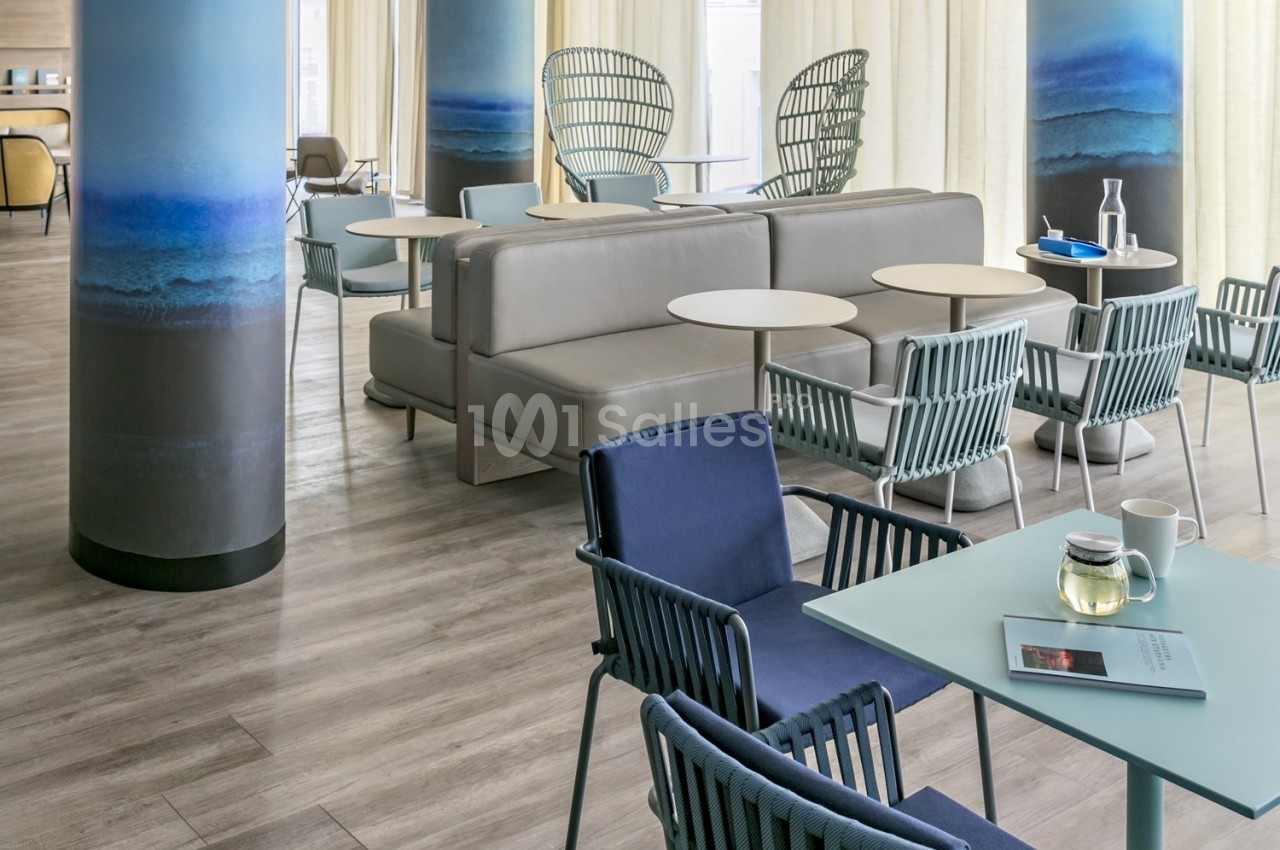 Espace lumineux avec des tables, chaises modernes et colonnes décorées, dans un cadre intérieur contemporain.