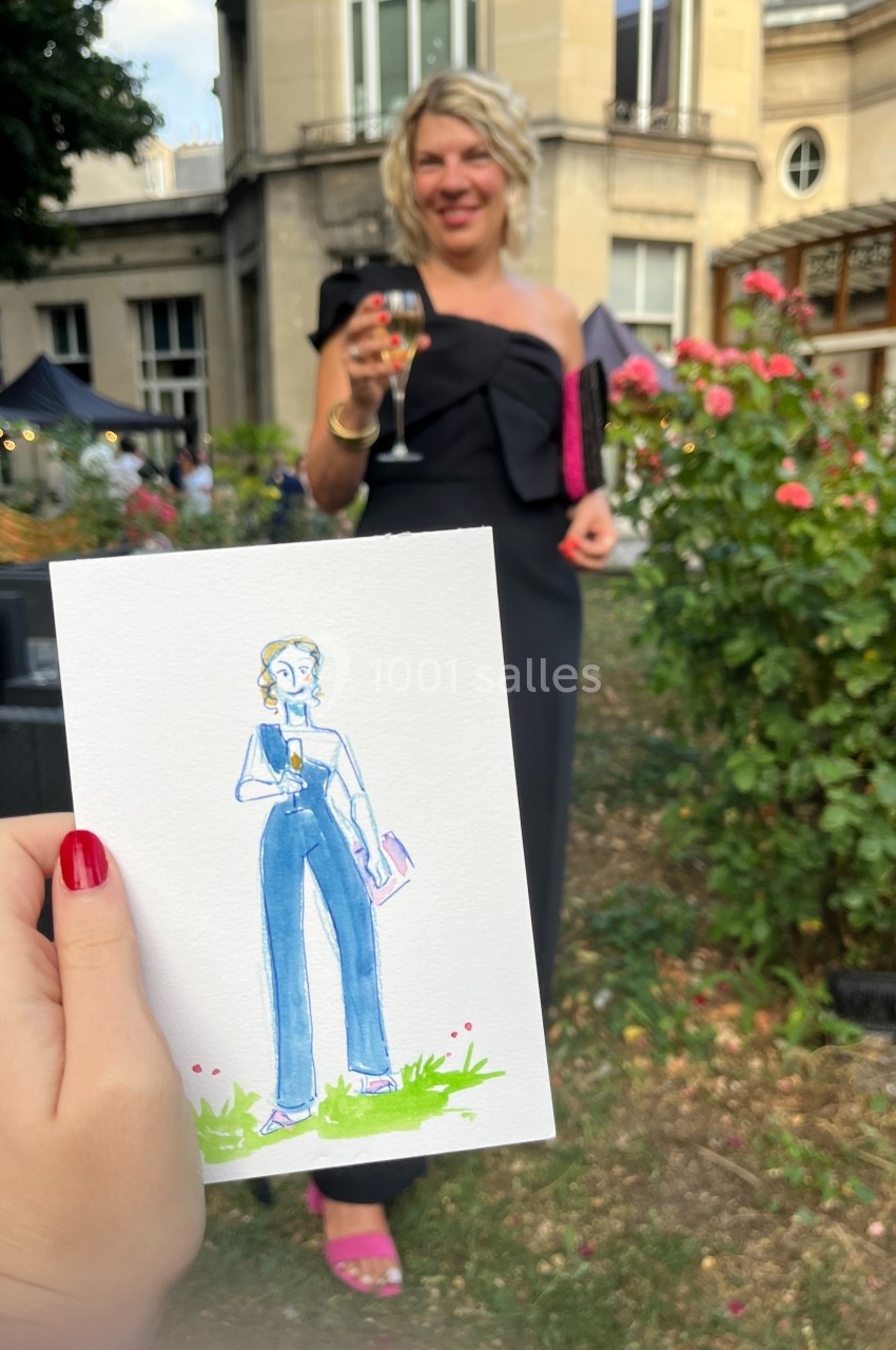 Une personne en robe noire tenant un verre de vin, avec un dessin d'elle-même tenu au premier plan.