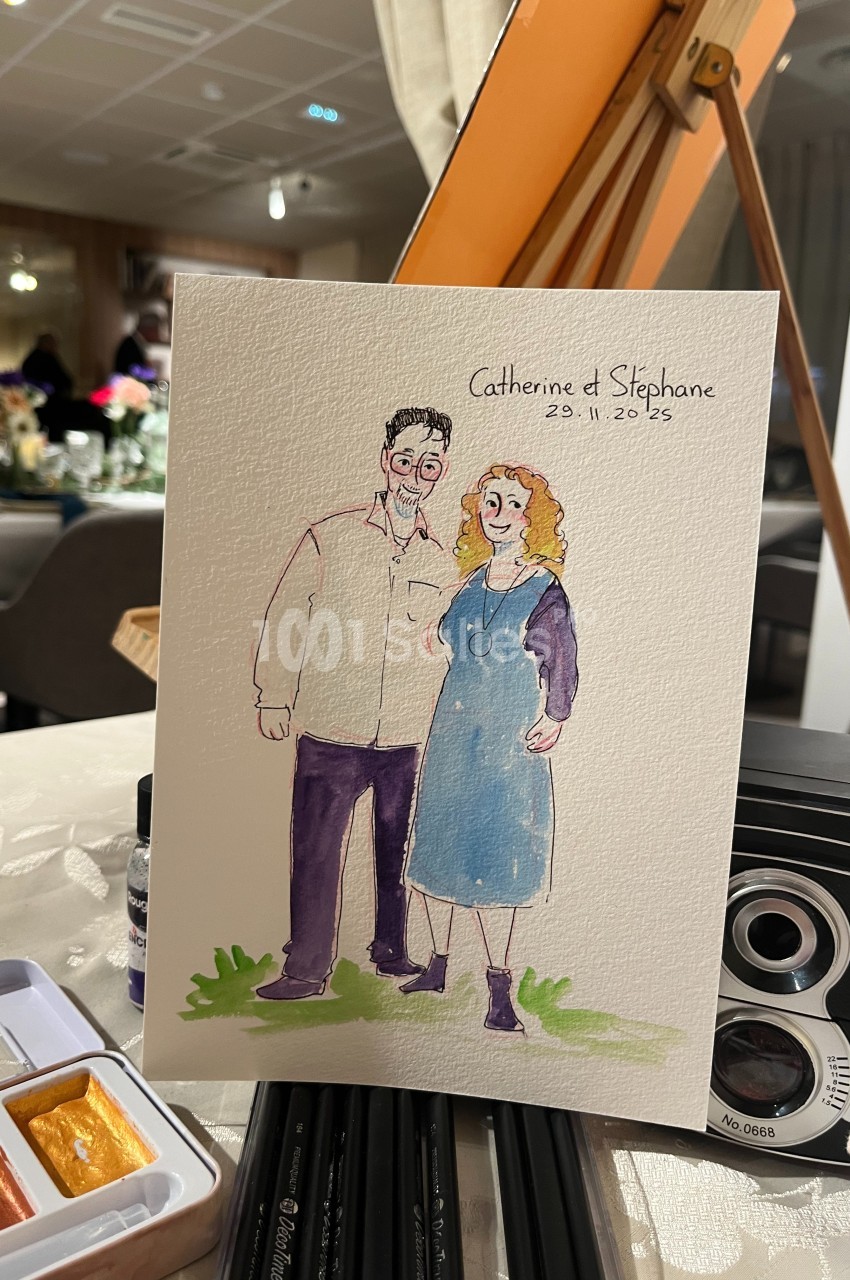 Illustration d'un couple souriant, peinte à l'aquarelle, posée sur une table avec des fournitures artistiques.