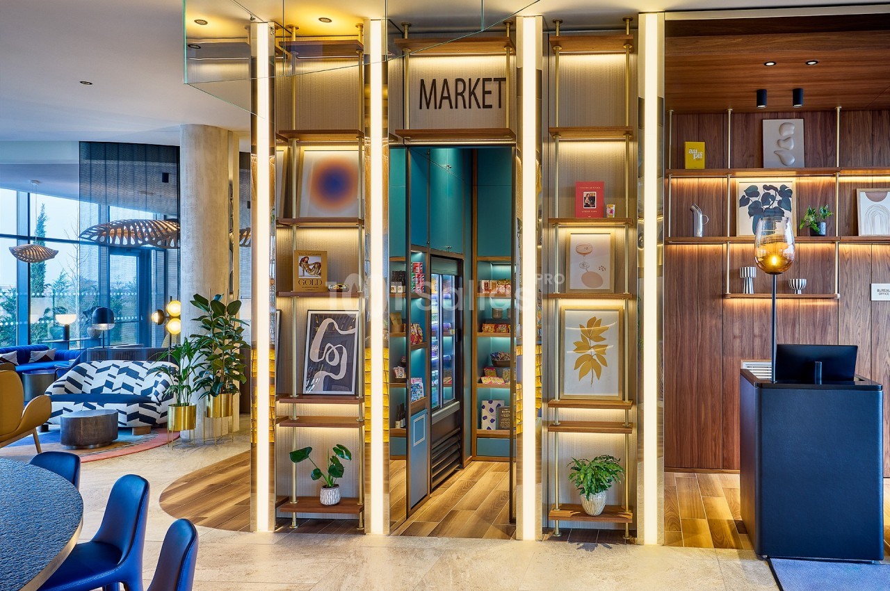 Vue d'un espace moderne avec un coin boutique ’Market’, des étagères illuminées et une décoration contemporaine.
