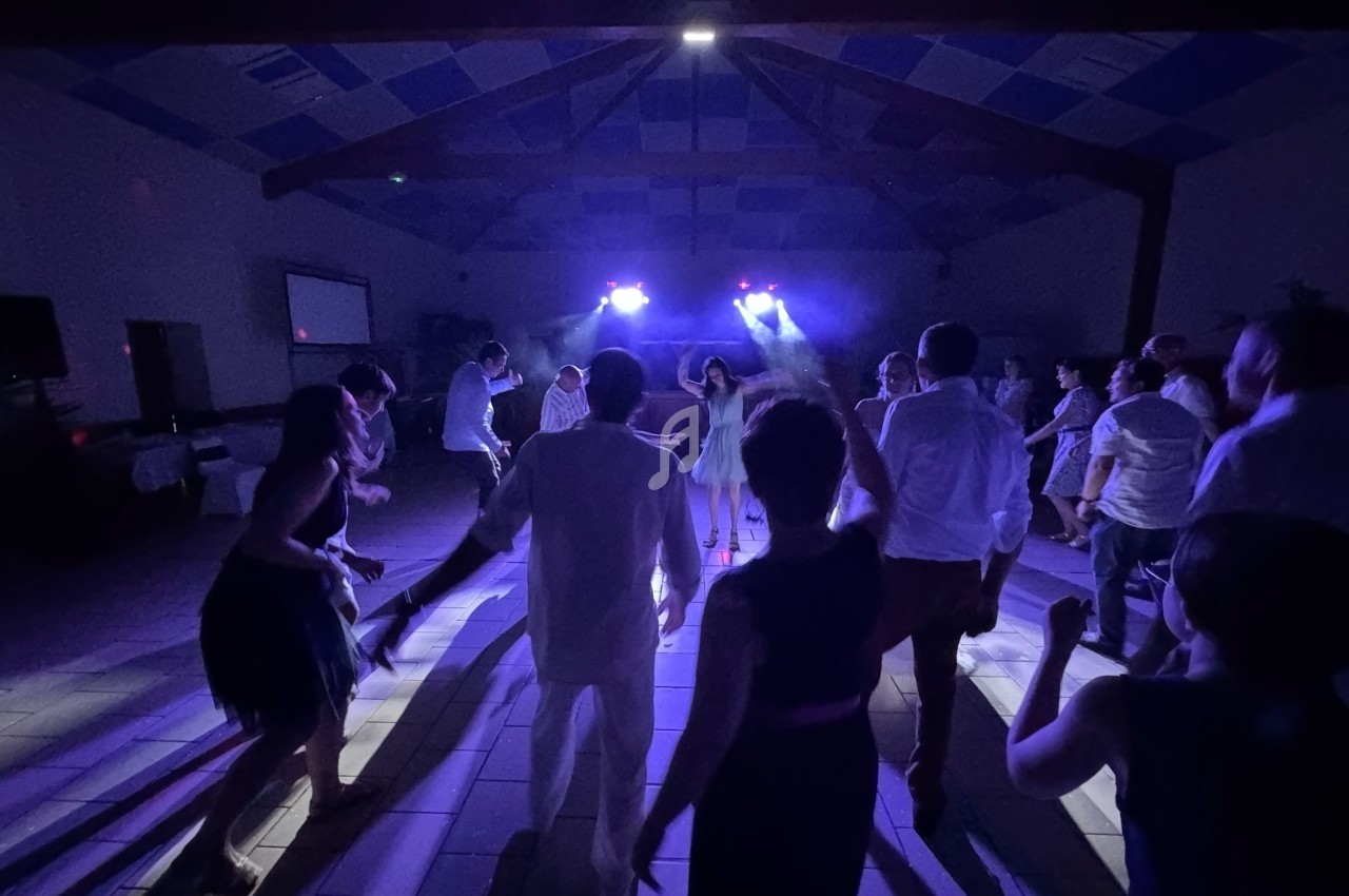 Groupe de personnes dansant dans une salle sombre éclairée par des lumières violettes.