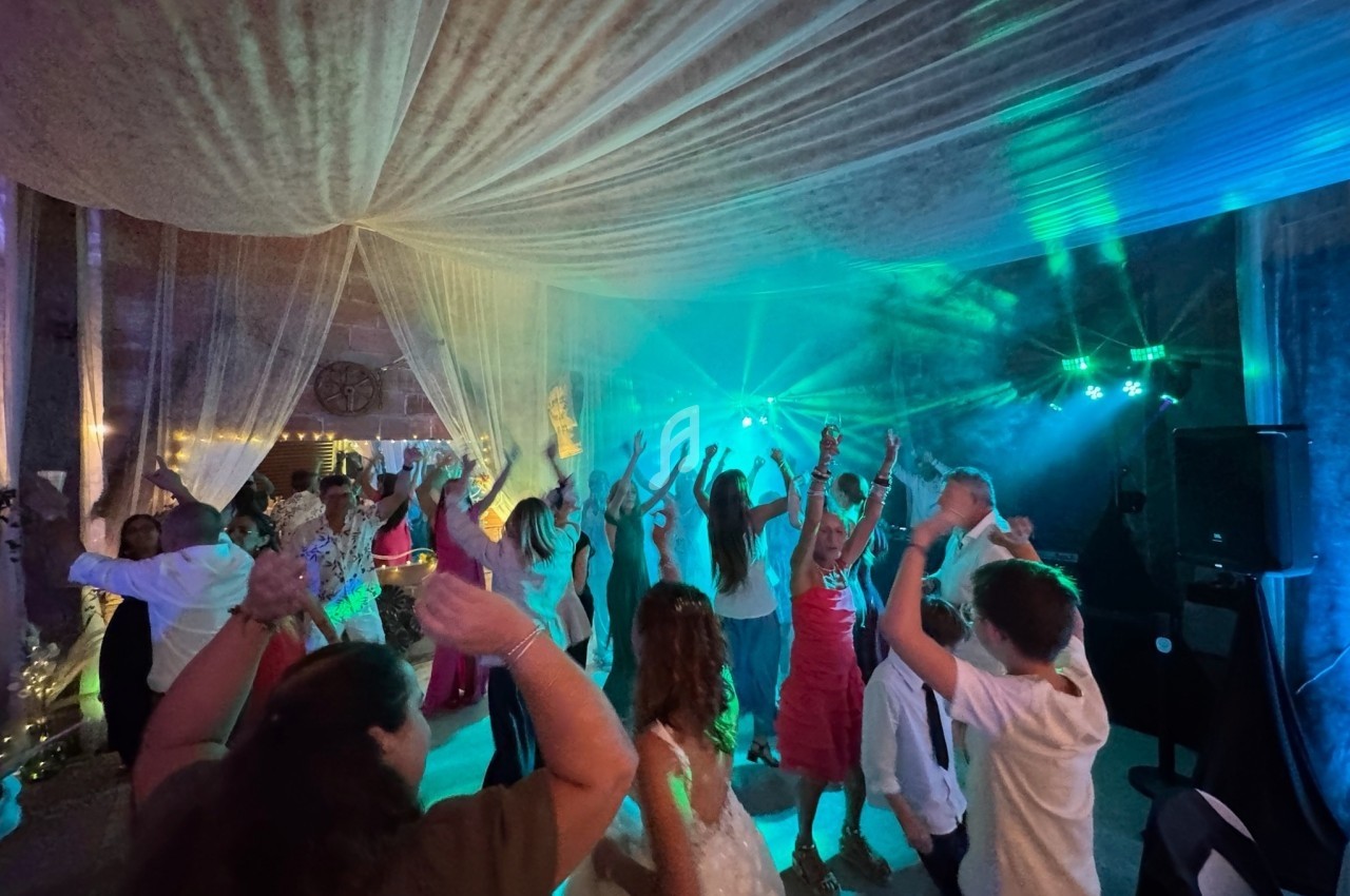 Personnes dansant sous une tente éclairée par des lumières colorées lors d'une fête ou d'un événement festif.