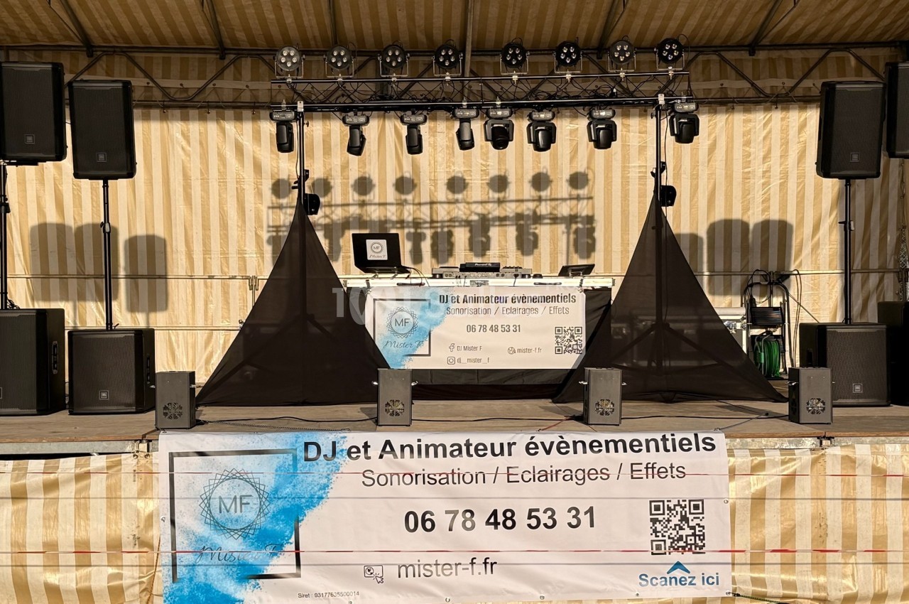 Installation de matériel de sonorisation et éclairage sur une scène extérieure avec une bannière publicitaire au premier…