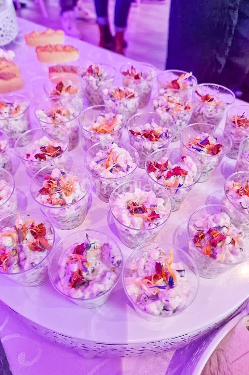 Verrines individuelles garnies d'une préparation colorée à base de légumes et fleurs comestibles, disposées sur une table.