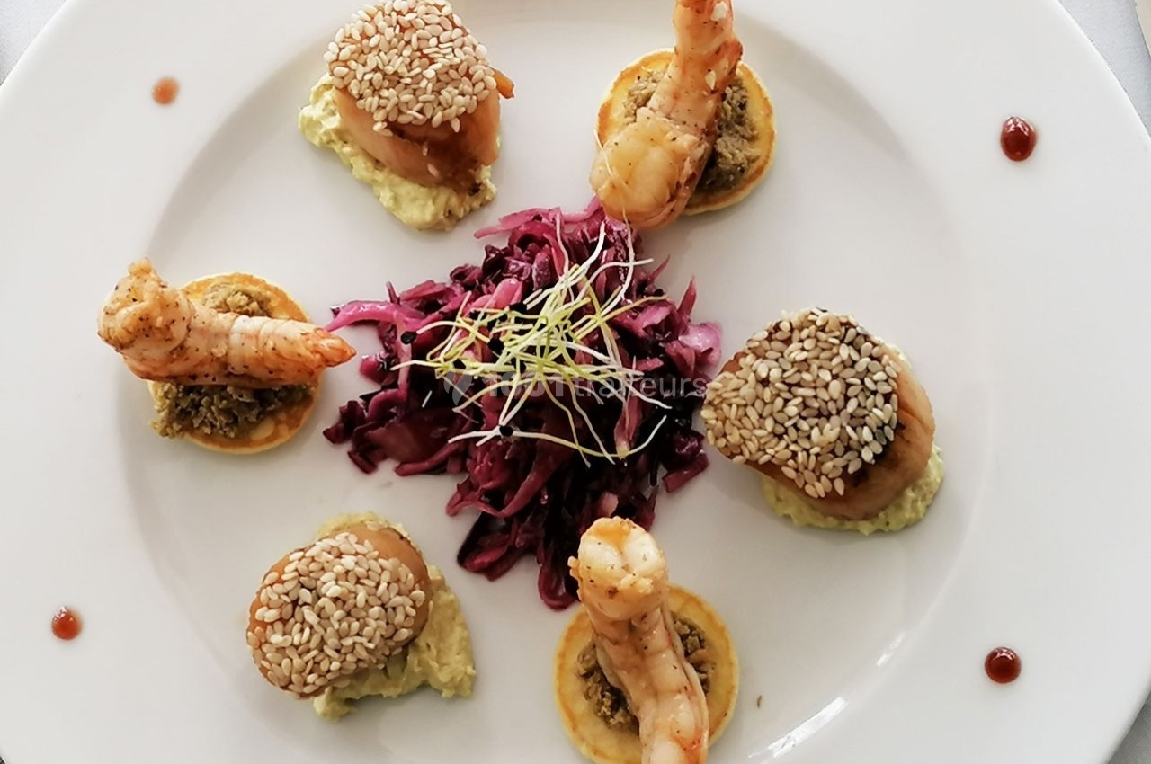 Assiette gastronomique composée de crevettes, noix de Saint-Jacques au sésame, choux rouges et purée sur mini-blinis.