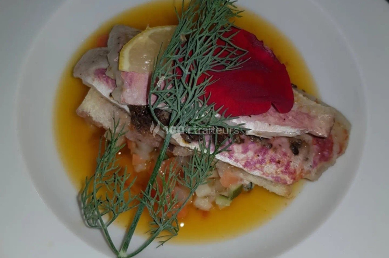 Assiette de filet de poisson sur lit de légumes, décorée d'aneth, d'une tranche de citron et d'un pétale rouge.