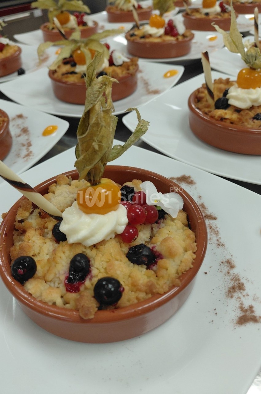Desserts individuels en ramequins avec crumble, fruits rouges, physalis, chantilly et décoration en chocolat.