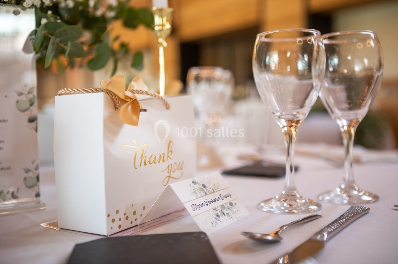 Boîte cadeau avec inscription ’thank you’ sur une table dressée, entourée de verres et d'éléments décoratifs.