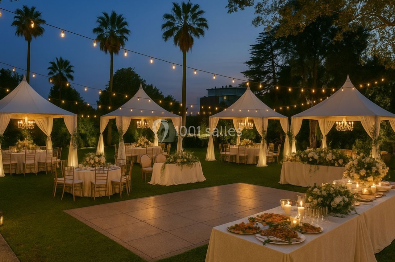 Tentes blanches éclairées, tables décorées et guirlandes lumineuses dans un jardin en soirée.