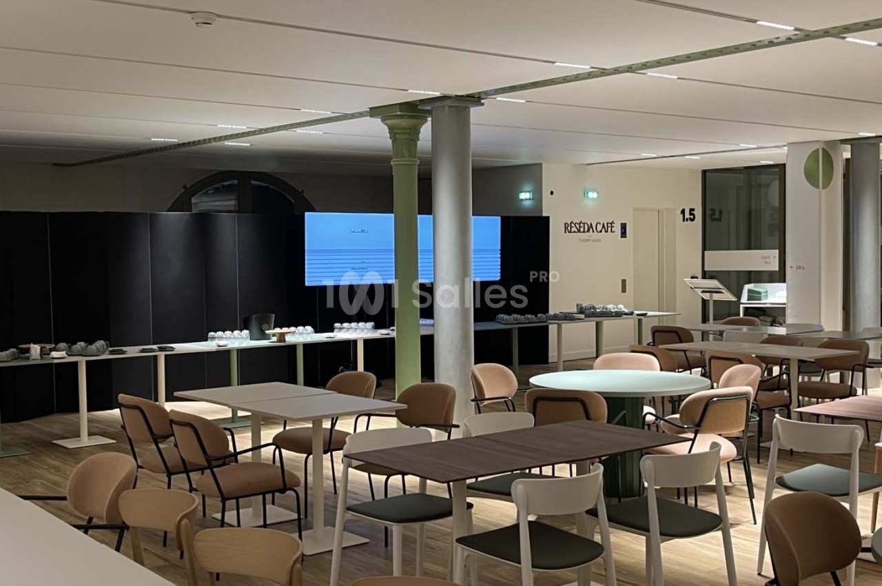 Salle de réunion moderne avec tables, chaises et écrans de présentation, éclairée par des lumières artificielles.