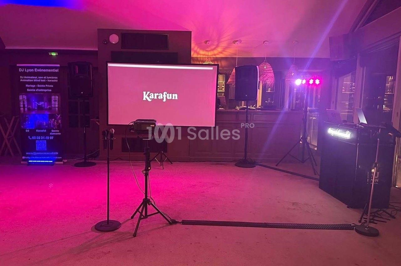 Équipement de karaoké installé dans une salle avec écran, micros sur pied, lumières colorées et matériel audio.