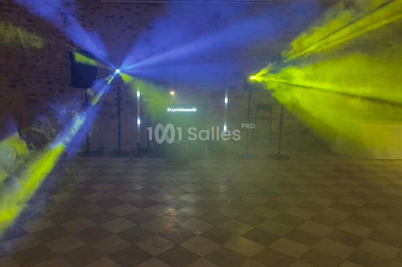 Jeu de lumières colorées bleues et jaunes projetées dans une salle avec sol carrelé et murs en pierre.
