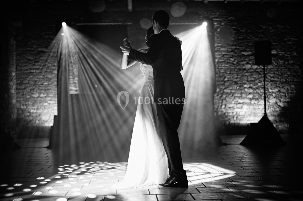 Un couple danse dans une salle faiblement éclairée, avec des projecteurs diffusant des faisceaux lumineux.