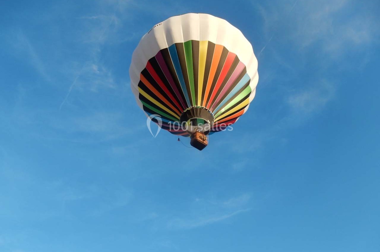 Montgolfière multicolore flottant dans un ciel bleu clair.