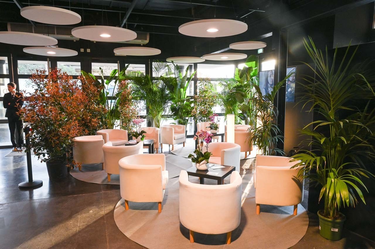 Espace intérieur lumineux avec fauteuils blancs, tables basses et plantes vertes dans un décor moderne et végétalisé.