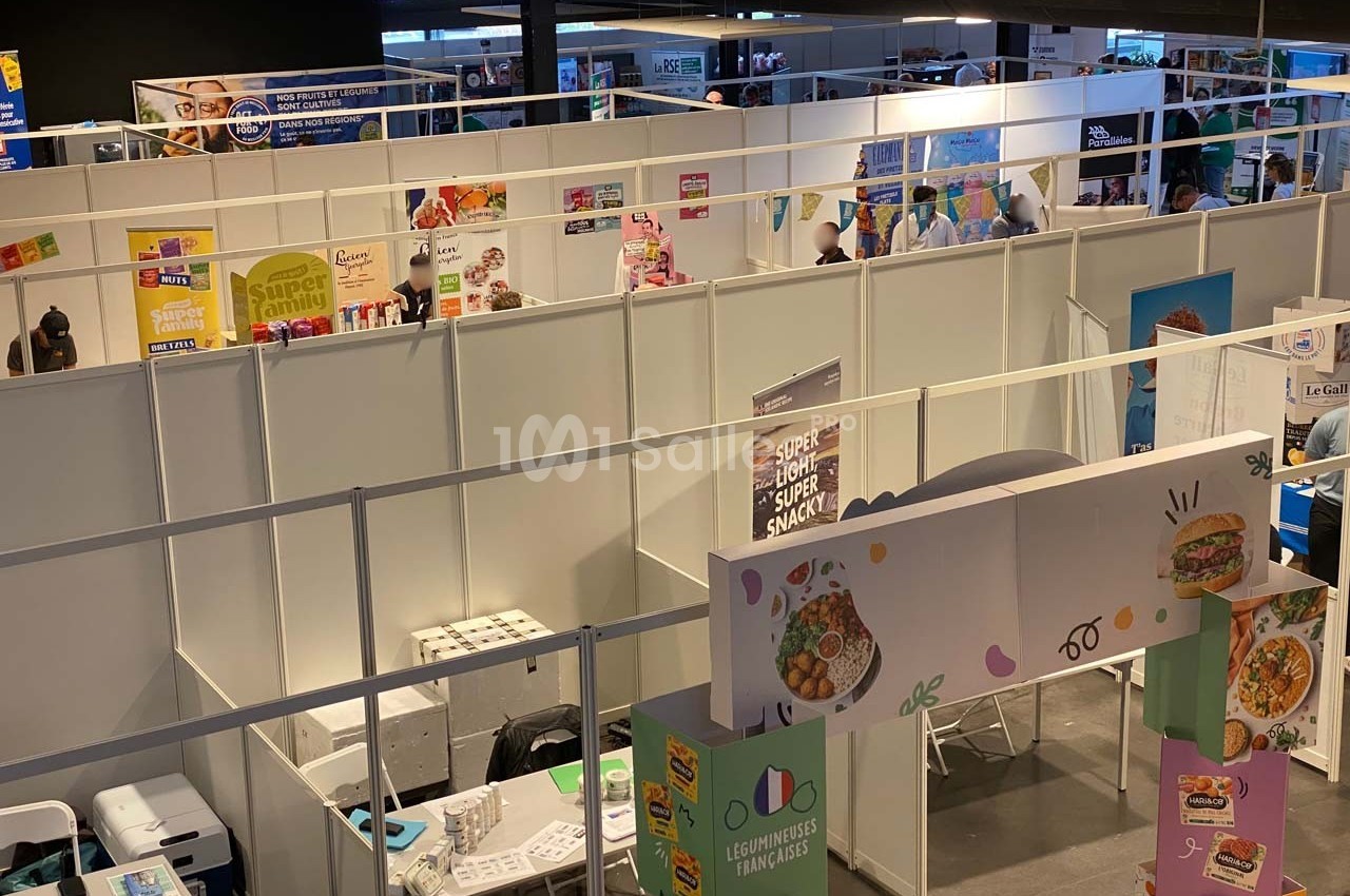 Vue d'un salon professionnel avec des stands exposant des produits alimentaires et des affiches promotionnelles.