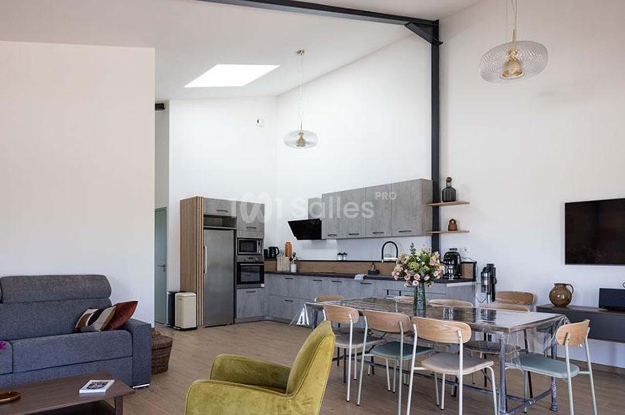 Salle à manger et cuisine ouverte modernes avec table en verre, chaises en bois, canapé, et décoration minimaliste.