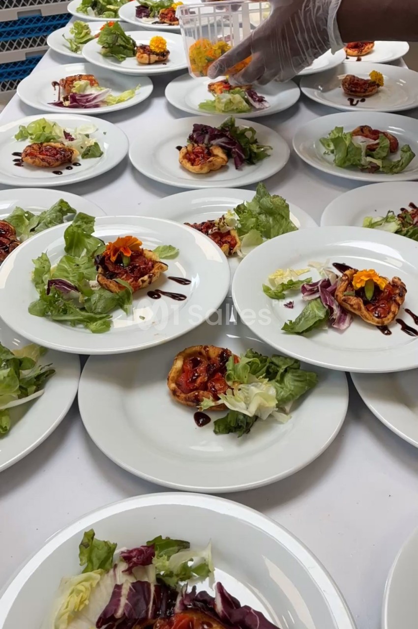Assiettes dressées avec des tartelettes garnies, salade verte et filet de sauce, préparées en cuisine.
