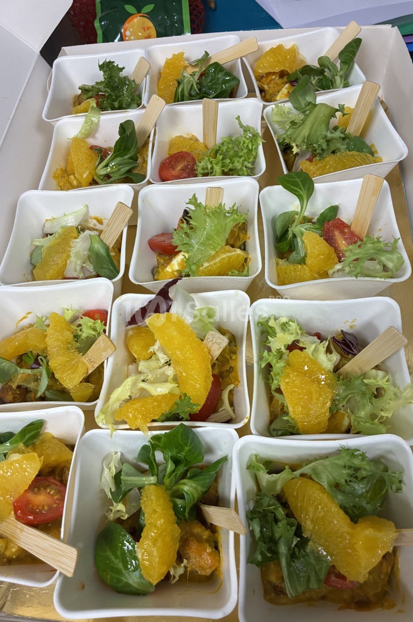 Assortiment de verrines contenant des salades colorées avec segments d'orange, tomates cerises et feuilles de salade.