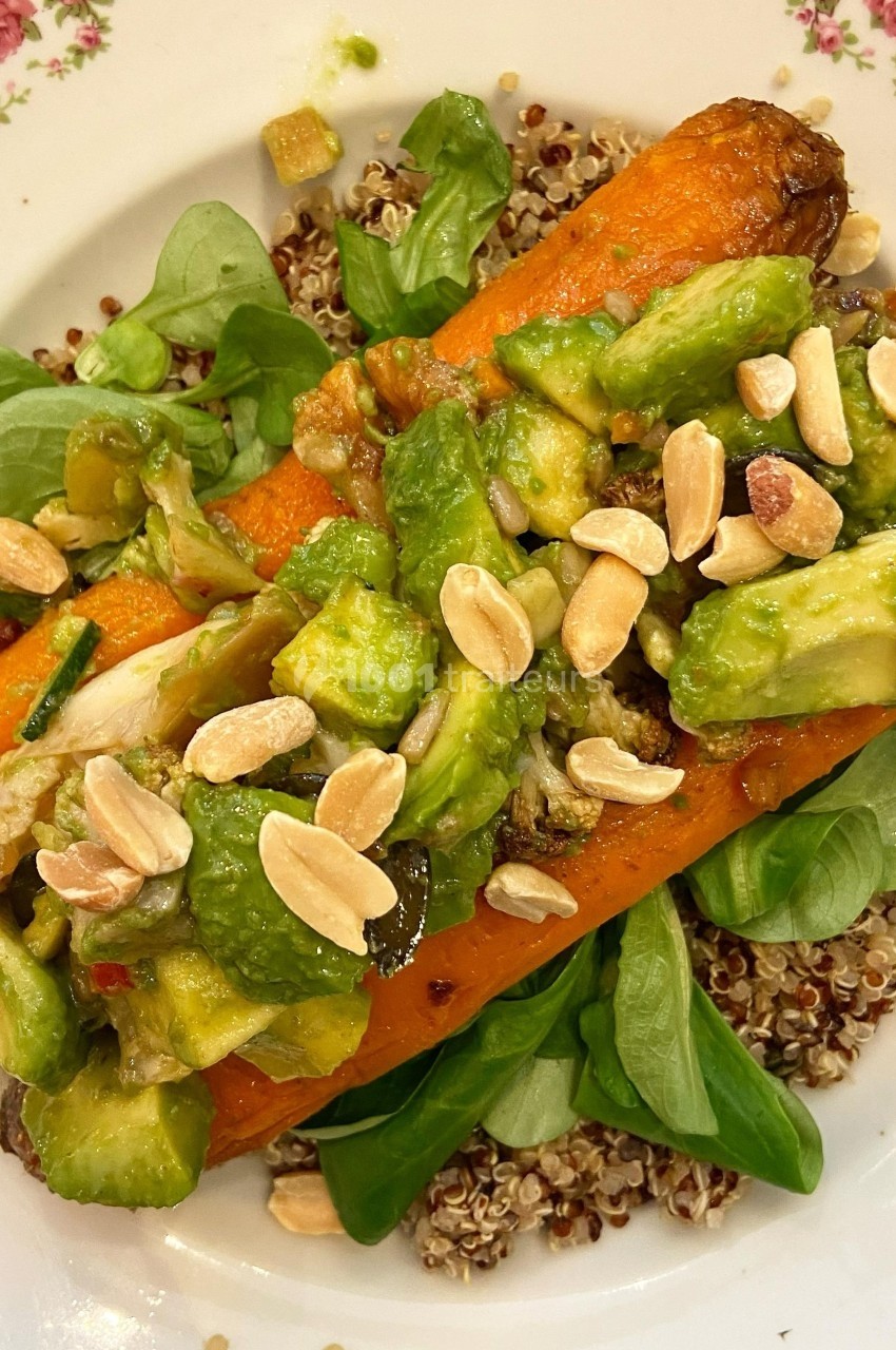 Assiette de quinoa garnie de carottes rôties, morceaux d'avocat, roquette et amandes effilées.