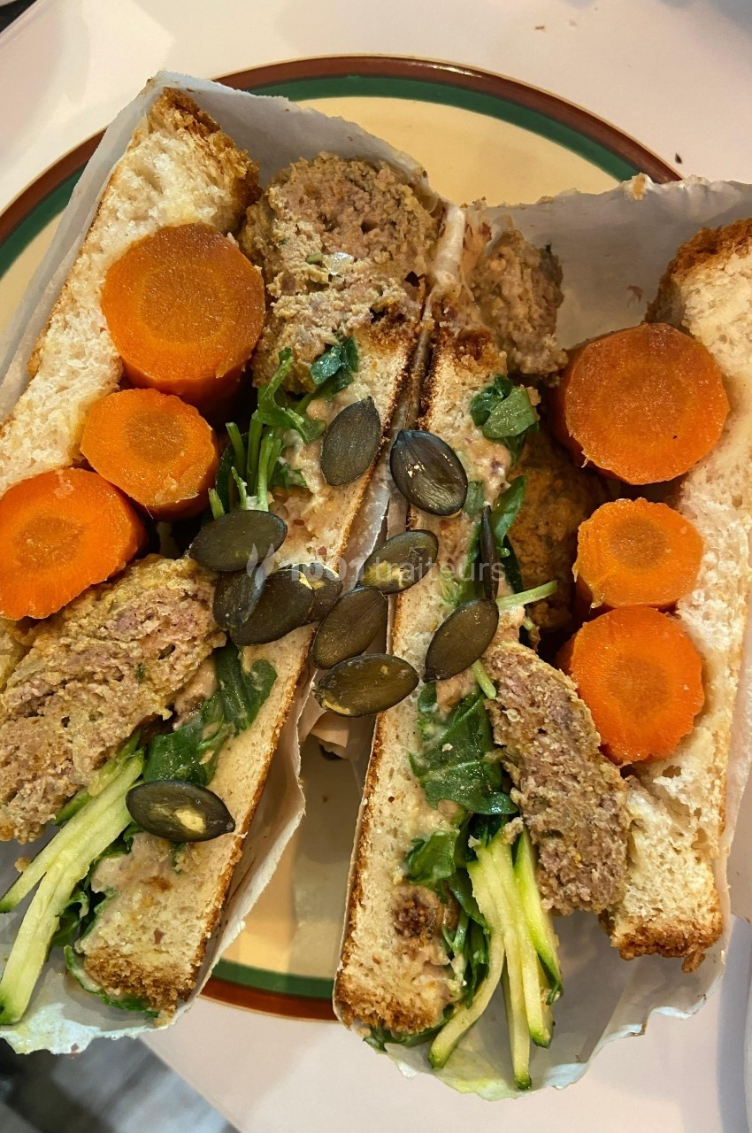 Sandwich garni de légumes frais, graines de courge, carottes en rondelles et une préparation à base de viande.