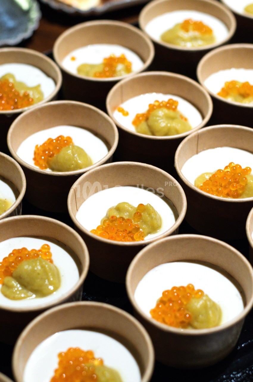 Petits pots en carton contenant une mousse blanche garnie de perles orange et d'une purée verte.