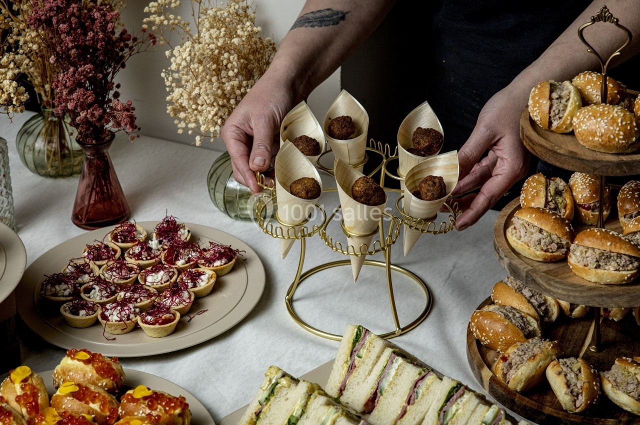 Plateau de buffet avec mini-sandwichs, bouchées apéritives, et fleurs séchées en arrière-plan.