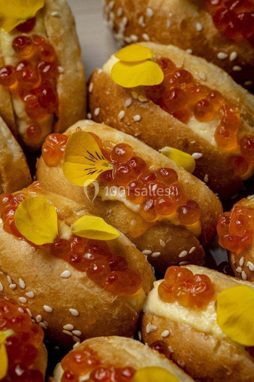 Petits pains garnis d'œufs de saumon, de crème et décorés de pétales de fleurs jaunes.