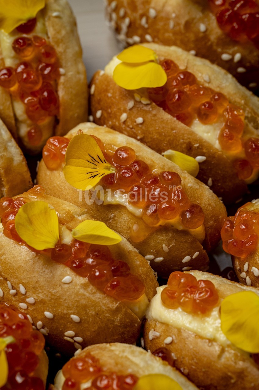 Petits pains garnis d'œufs de saumon, de crème et décorés de pétales de fleurs jaunes.