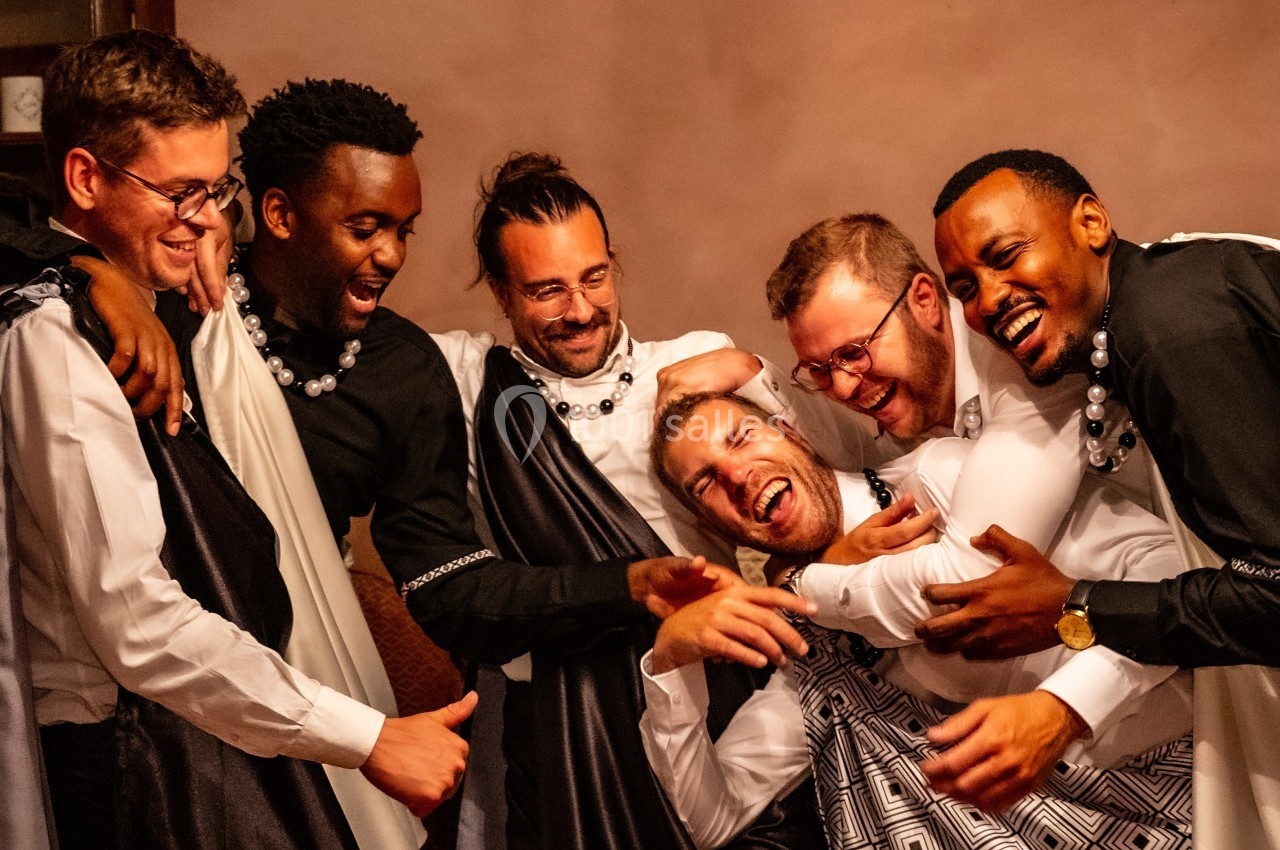 Un groupe d'hommes souriants vêtus de tenues traditionnelles, partageant un moment de convivialité.