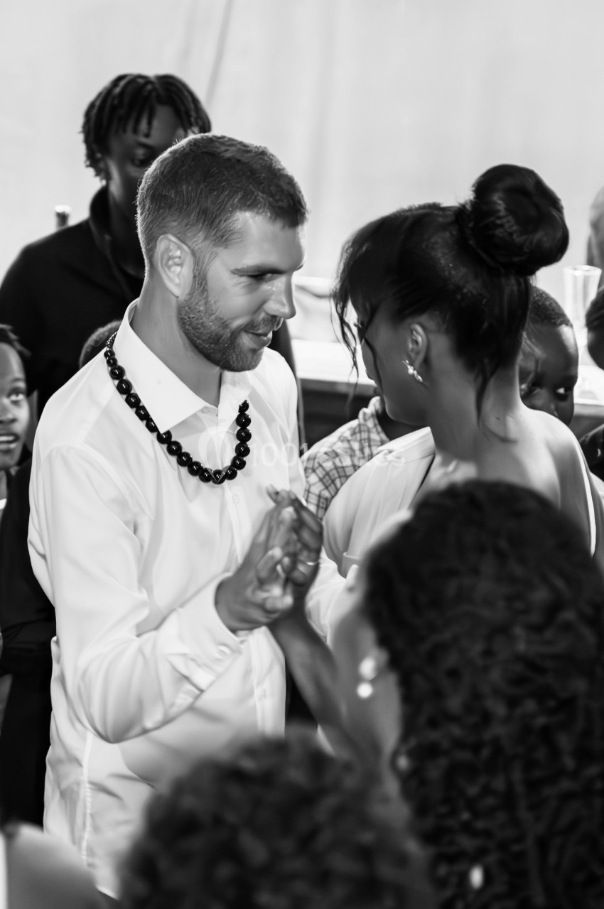 Un homme et une femme dansent ensemble lors d'un événement, entourés de plusieurs personnes en arrière-plan.