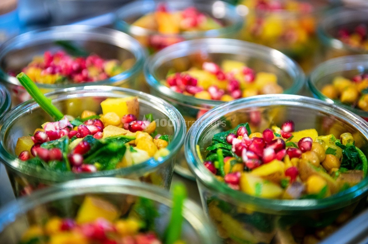Salades colorées en bocaux avec pois chiches, épinards, morceaux de légumes et graines de grenade.