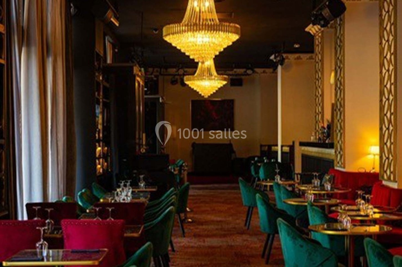 Salle élégante avec tables dressées, chaises colorées, lustres en cristal suspendus et éclairage tamisé.