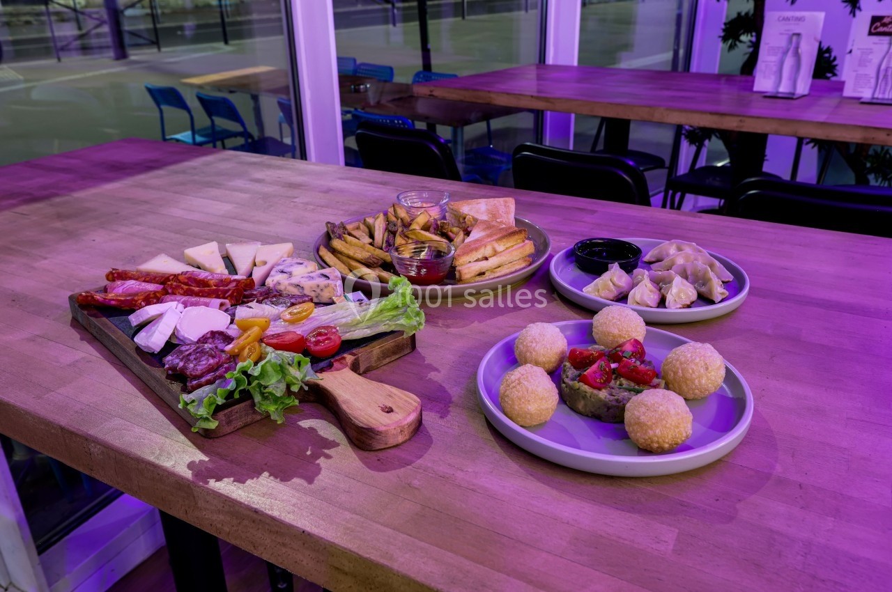 Plateaux de charcuterie, fromages, frites, raviolis et boulettes servis sur une table en bois dans un restaurant.