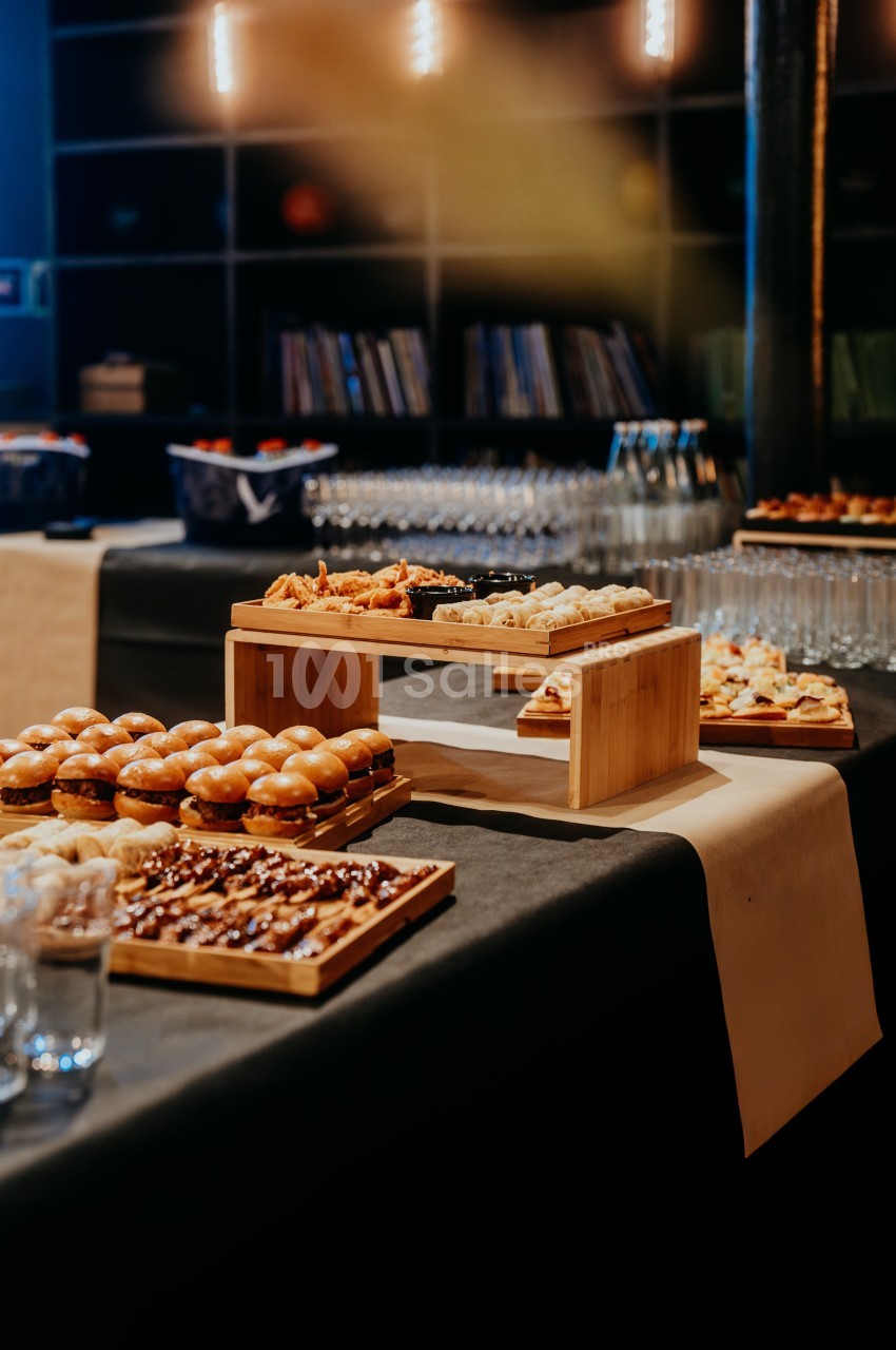 Buffet avec divers plats, dont mini-sandwichs, desserts et amuse-bouches, disposés sur une table noire.