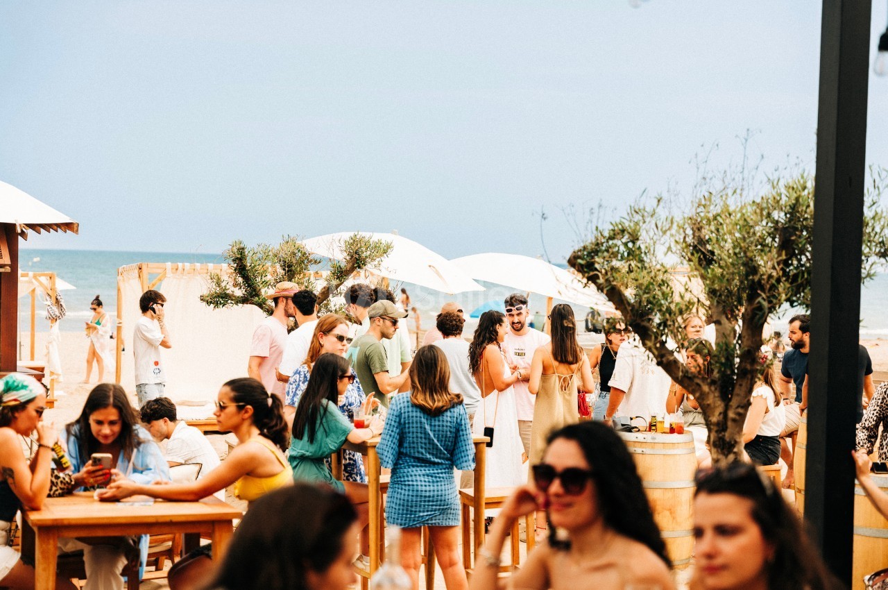 Groupe de personnes discutant et partageant un moment convivial dans un espace extérieur près de la plage.
