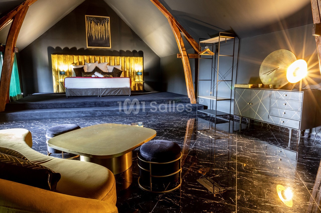 Chambre mansardée avec lit double, mobilier moderne, éclairage chaleureux et sol en marbre noir.