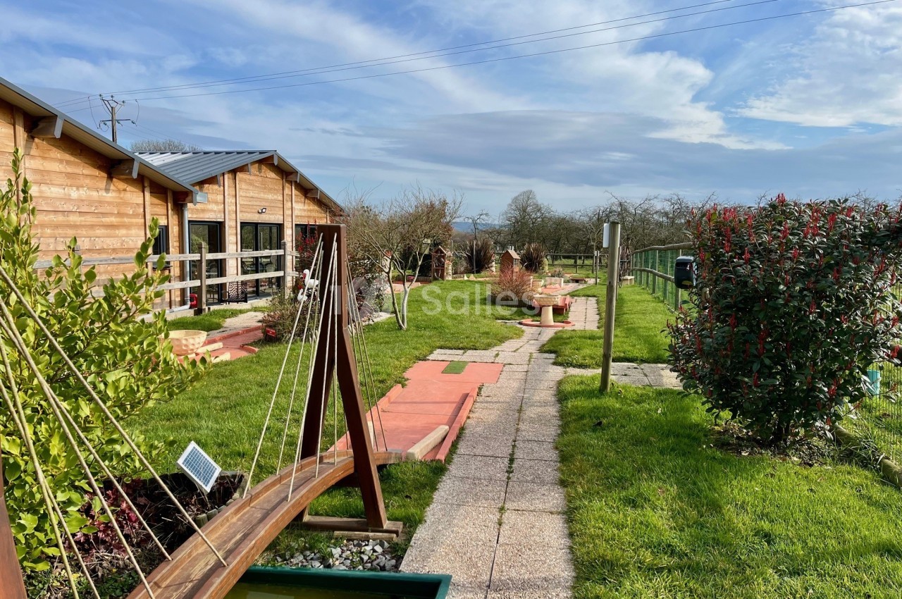 Allée pavée bordée de verdure, avec un mini-golf et des bâtiments en bois sous un ciel dégagé.