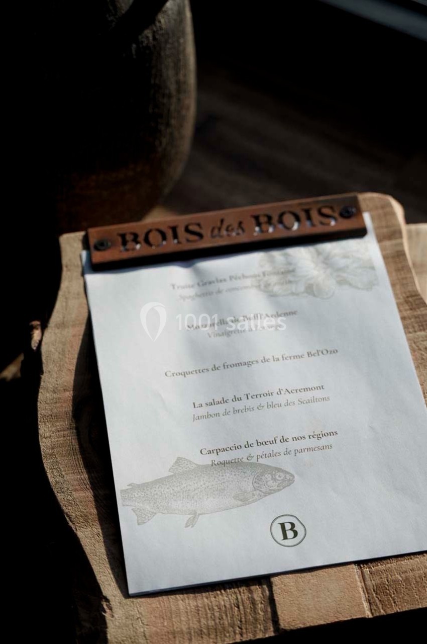Carte de menu posée sur une planche en bois, éclairée par une lumière naturelle, avec des plats inscrits en texte.