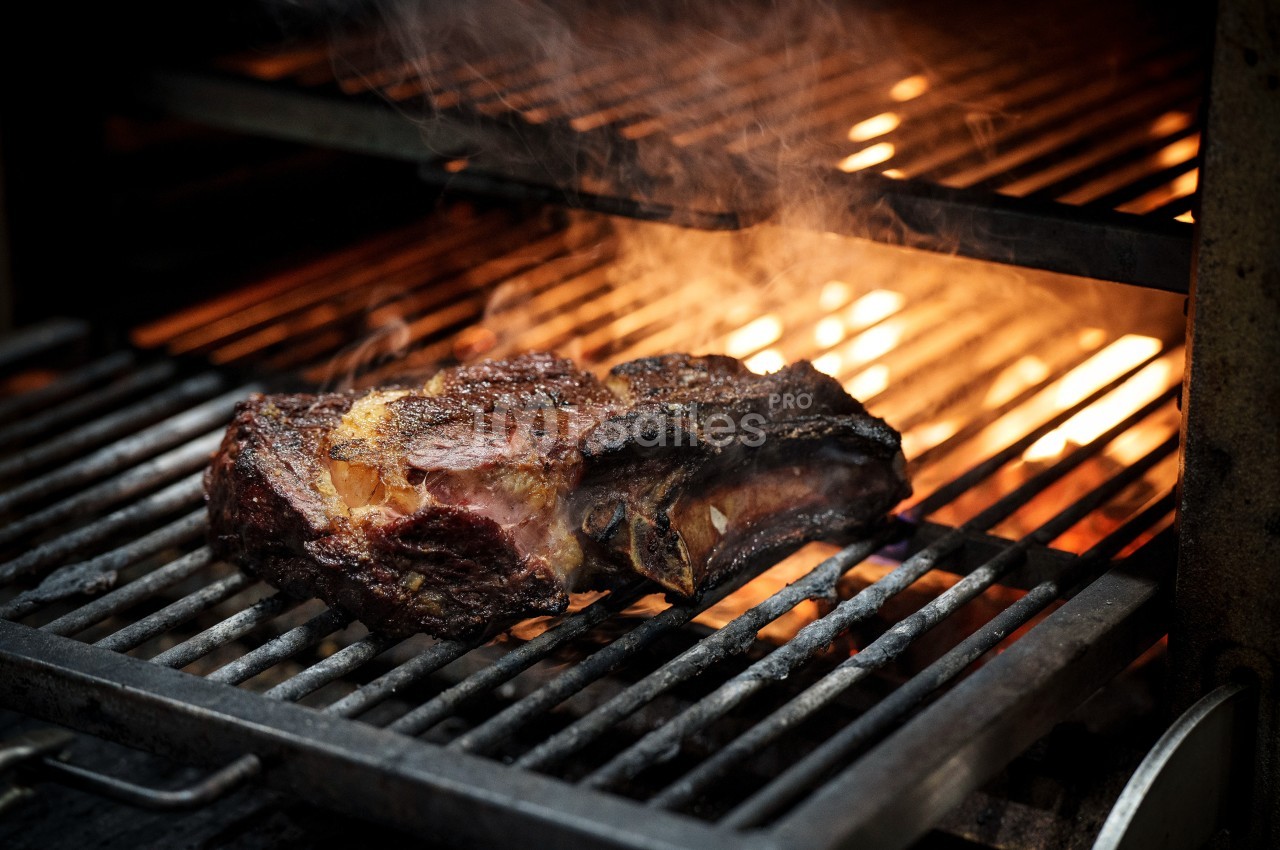 Viande grillée sur un barbecue avec des flammes et de la fumée en arrière-plan.