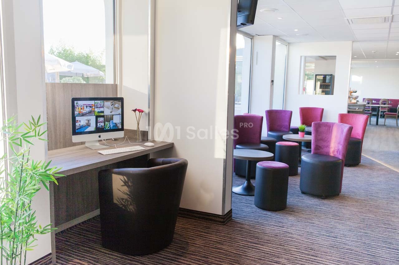 Espace détente avec fauteuils colorés et coin bureau équipé d'un ordinateur dans un intérieur lumineux.