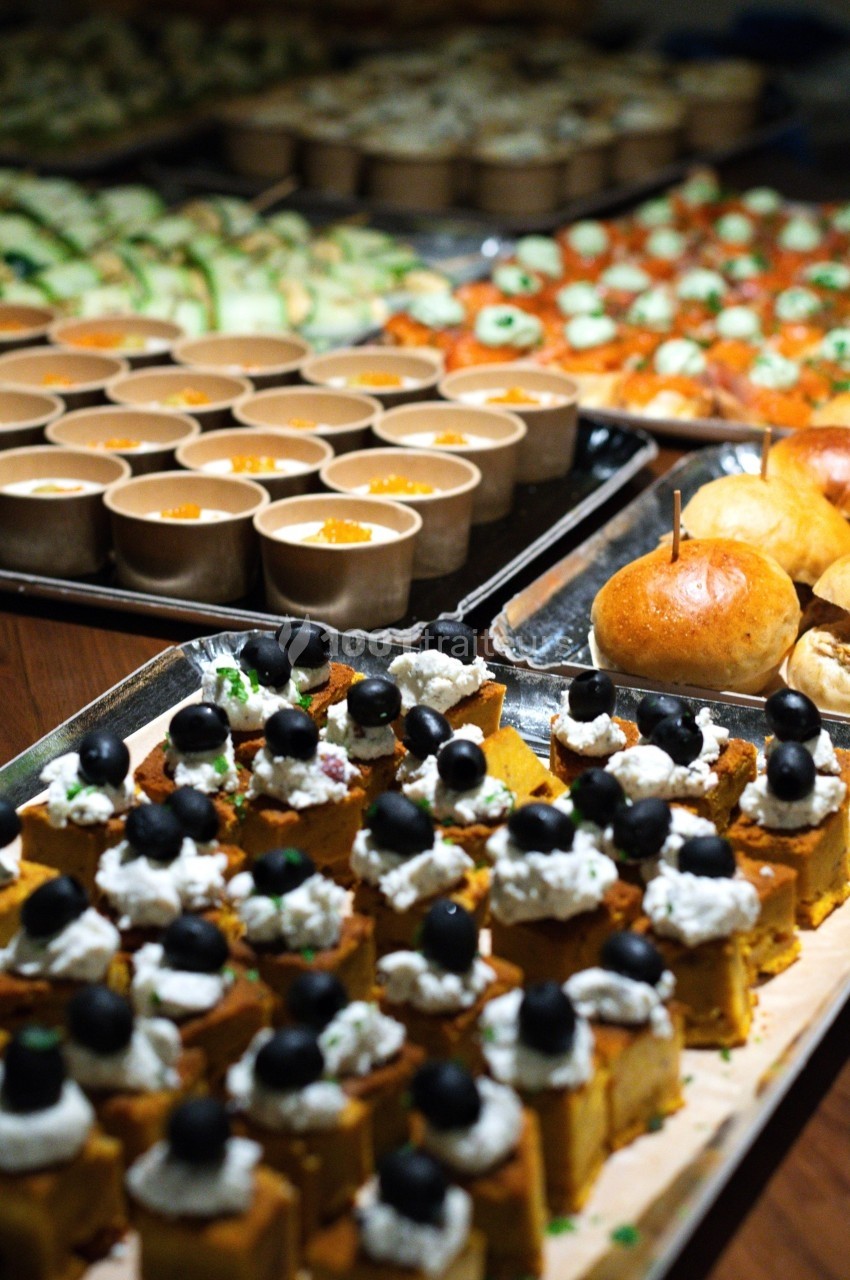 Plateaux de bouchées apéritives variées, incluant des verrines, des pains et des amuse-bouches garnis d'olives noires.