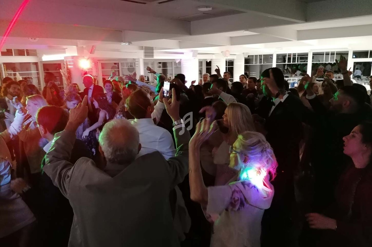 Des personnes dansent et s'amusent lors d'une soirée animée dans une salle éclairée par des lumières colorées.